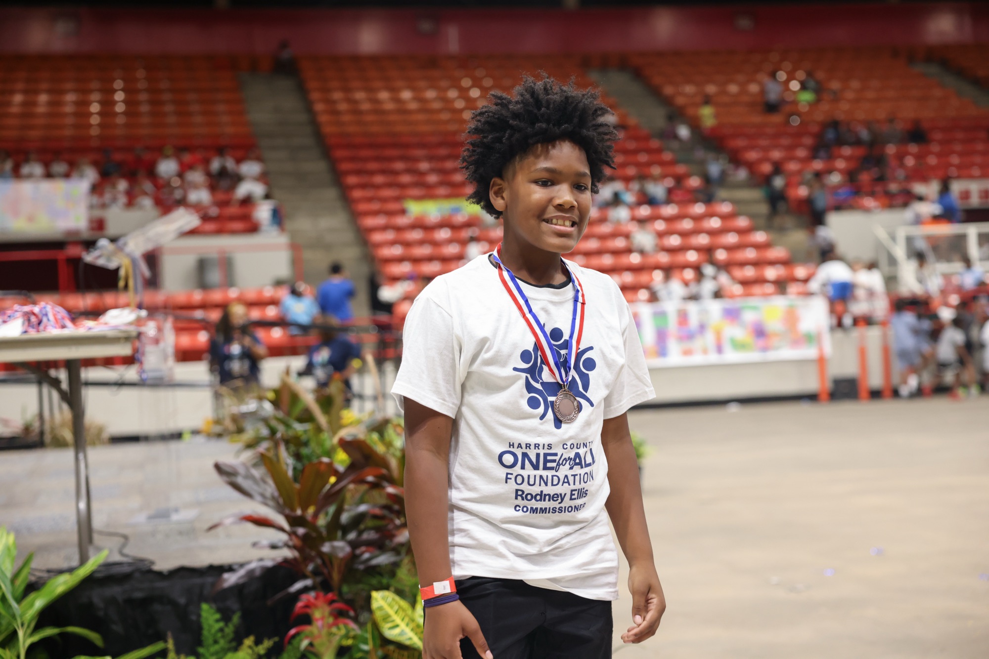 Young medal winner wearing a Harris County One For All Foundation shirt at the summer final games
